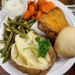 Fried chicken with carrots, green beans and a potato on a plate.