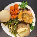Stuffed porkloin with carrots, green beans and a potato on a plate.