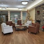 The lobby decorated for Christmas with a Christmas tree, fireplace and chairs.