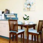 Kitchen with small fridge, microwave, table and two chairs.