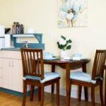 Kitchen with small fridge, microwave, table and two chairs.