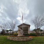 Front of building with flag and flowers.