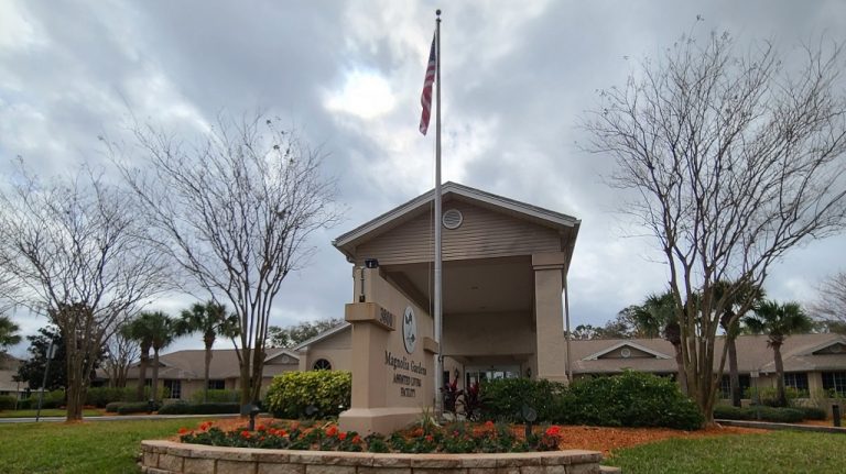 Front of building with flag and flowers.