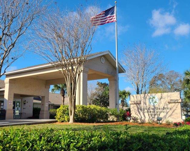 Front entrance side view with flag and Magnolia Gardens sign.